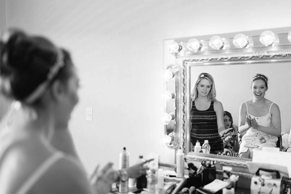 black and white picture of bride looking at herself in the mirror at the Post Card Inn bridal suite