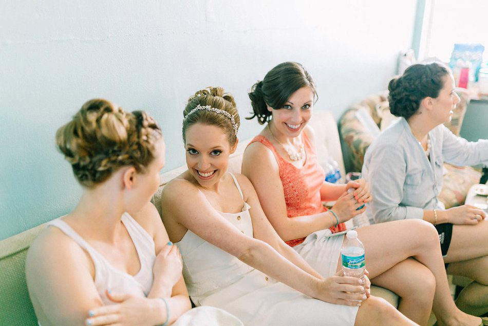 photo of bride sitting on the couch with her bridesmaids in the bridal suite of the Post Card Inn