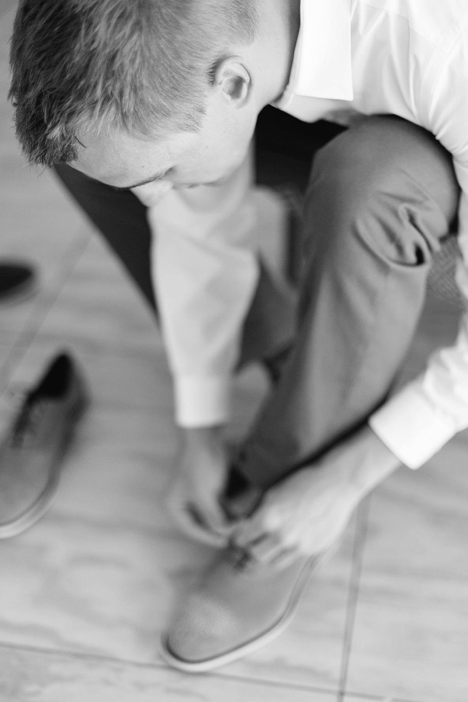 black and white photo of the groom tying his shoes. Destination wedding at the Postcard Inn on the Beach by Catherine Ann Photography