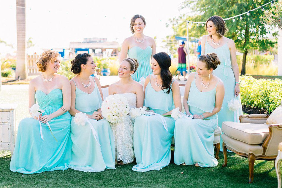 Photo of bridesmaids sitting on a vintage couch in a wedding lounge. Outdoor wedding lounge inspiration. Destination wedding at the Postcard Inn on the Beach by Catherine Ann Photography
