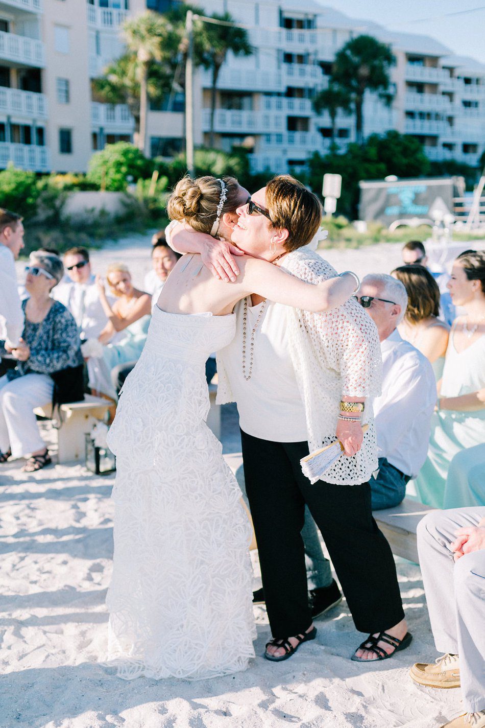 Bride hugging her mom during the ceremony. Destination wedding at the Postcard Inn on the Beach by Catherine Ann Photography