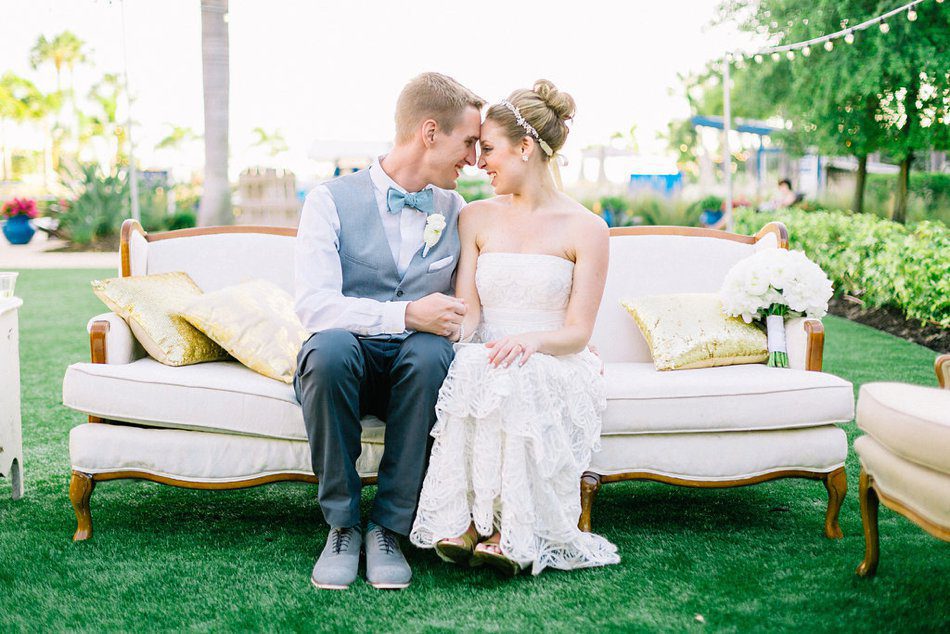 Romantic bride and groom photo sitting on a vintage couch in a garden by Catherine Ann Photography 