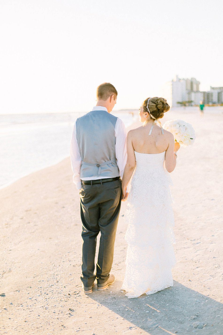 beautiful photo of bride and groom walking on the beach in Tampa Florida. Destination wedding at the Postcard Inn on the Beach by Catherine Ann Photography