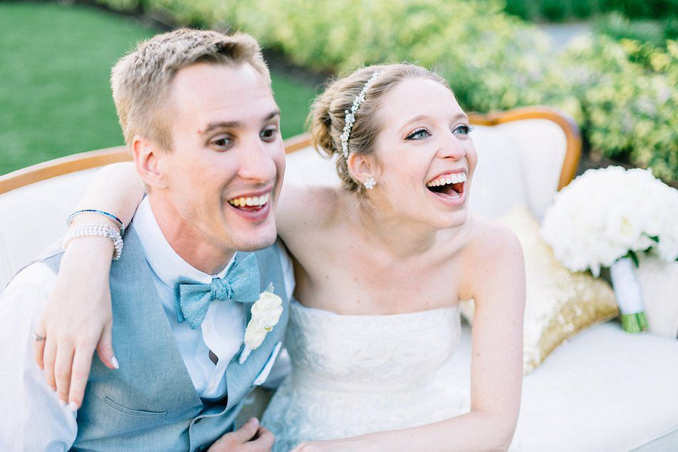 Photo of happy bride and groom sitting on an antique couch