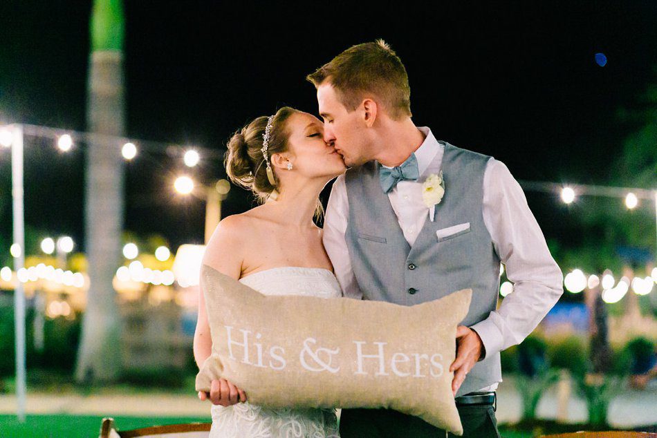 Night time wedding photo of bride and groom kissing under cafe lights. Destination wedding at the Postcard Inn on the Beach by Catherine Ann Photography