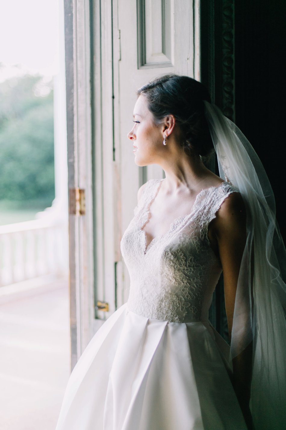 Natural light bridal portrait of bride looking out the door