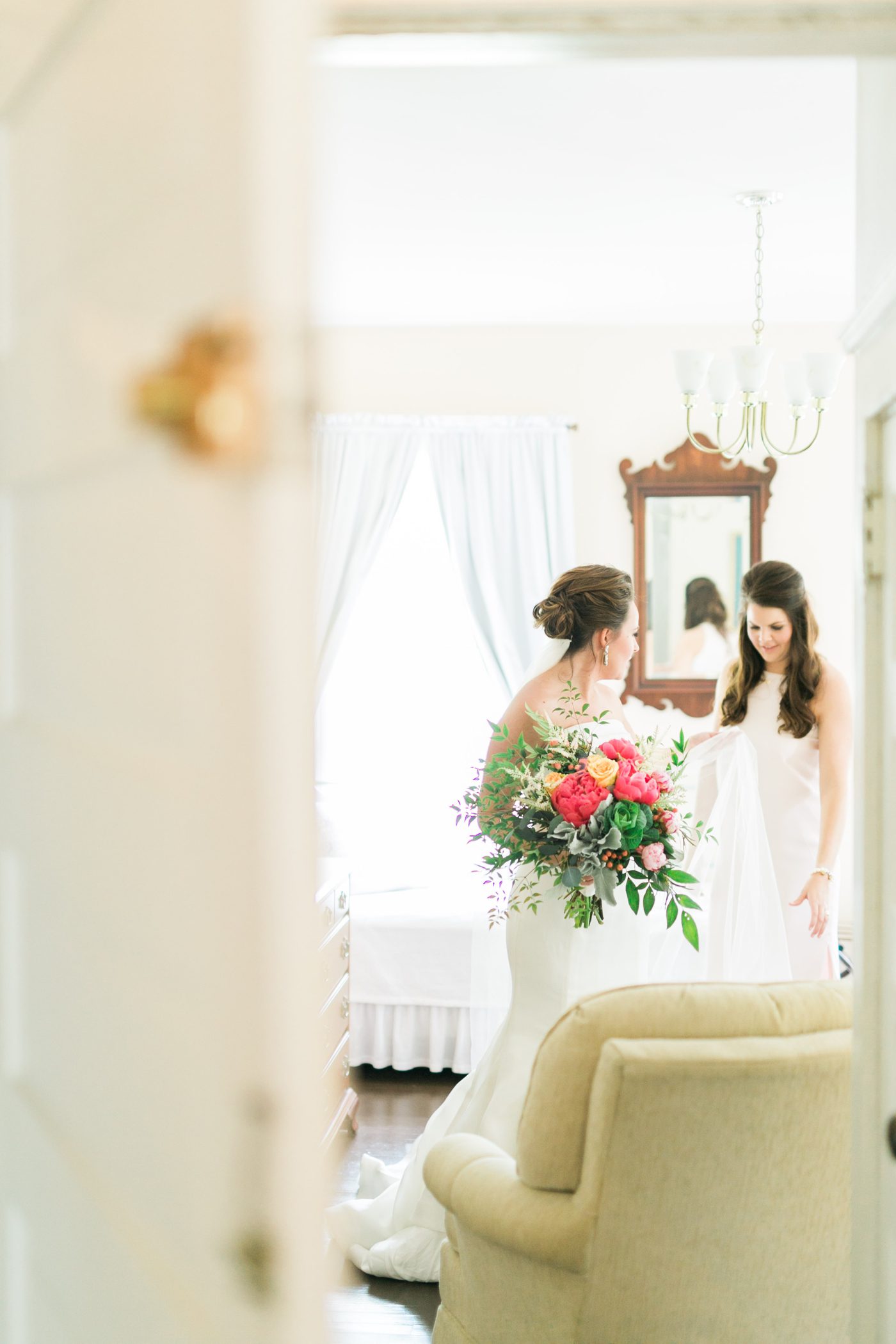 Candid photo of bridesmaid helping the bride get ready. Photo by Charleston wedding photographer Catherine Ann Photography
