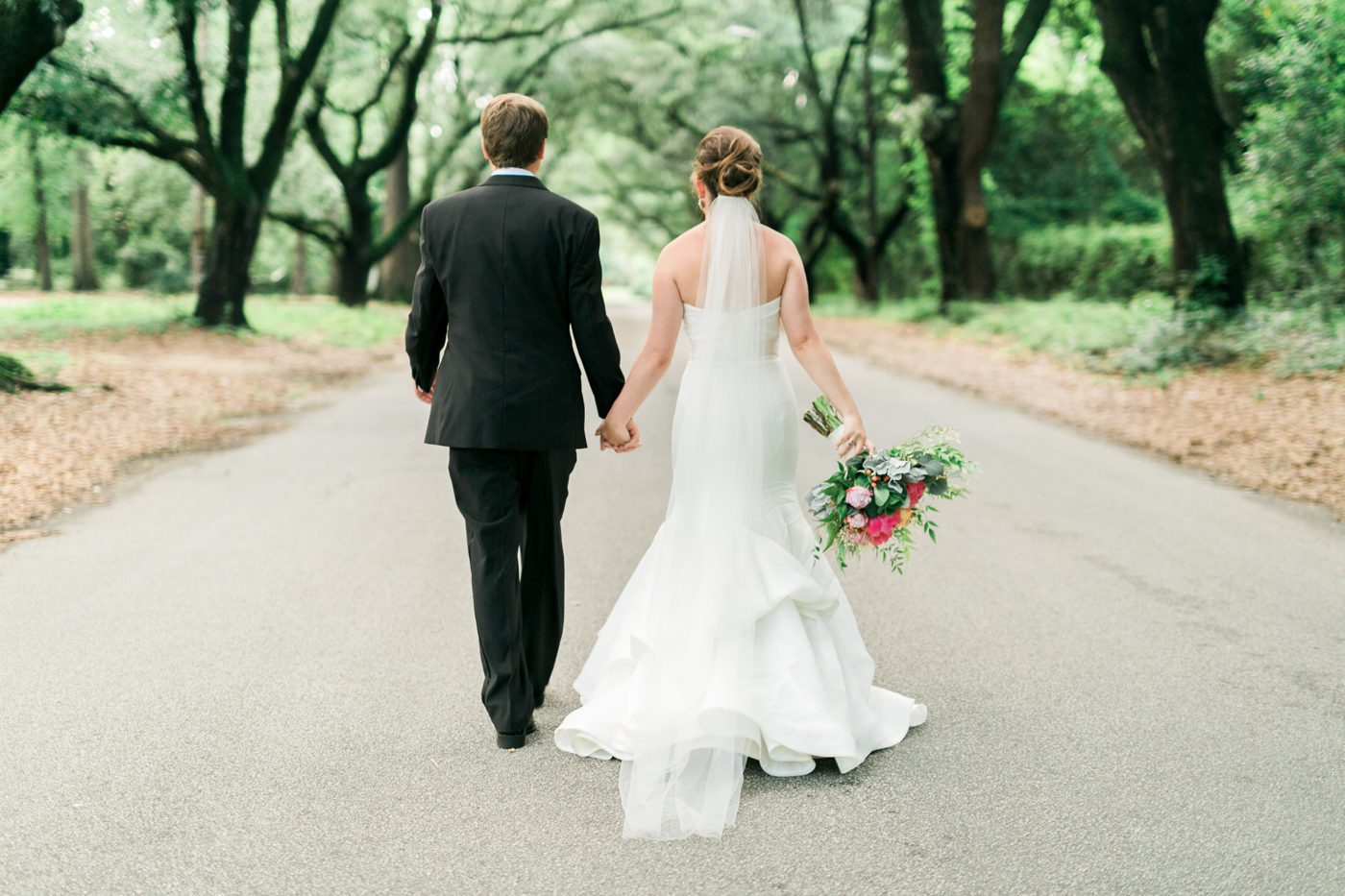 Photo of bride and groom walking away under avenue of oaks in South Carolina. Photo by Charleston wedding photographer Catherine Ann Photography