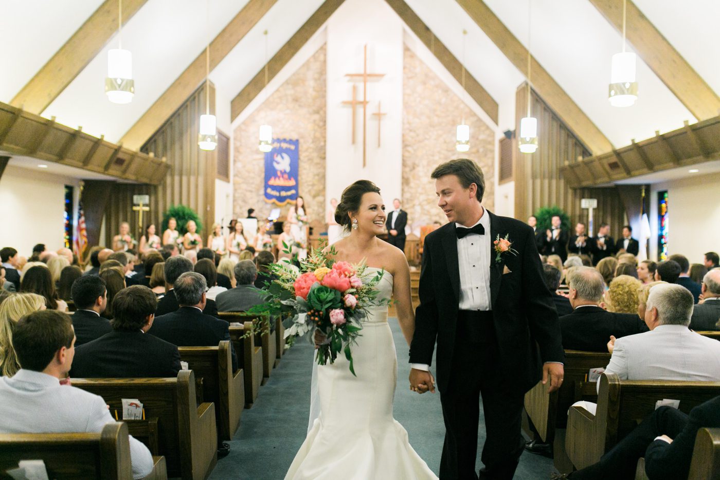 Bride and groom walking down the aisle together smiling. Photo by Charleston wedding photographer Catherine Ann Photography