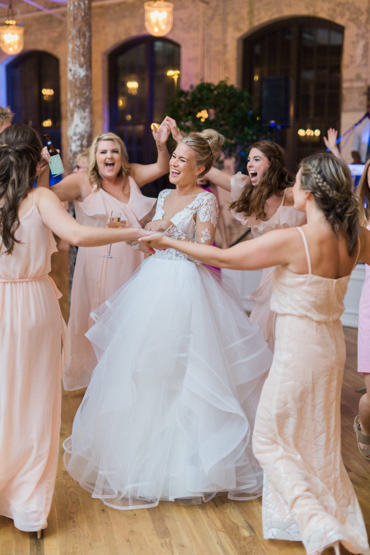 Fun reception picture of bridesmaids dancing in a circle around the bride at the Cedar Room