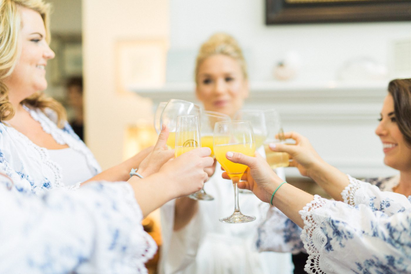 Photo of bride and bridesmaids cheersing with mimosas the morning of the wedding. Photo by Catherine Ann Photography
