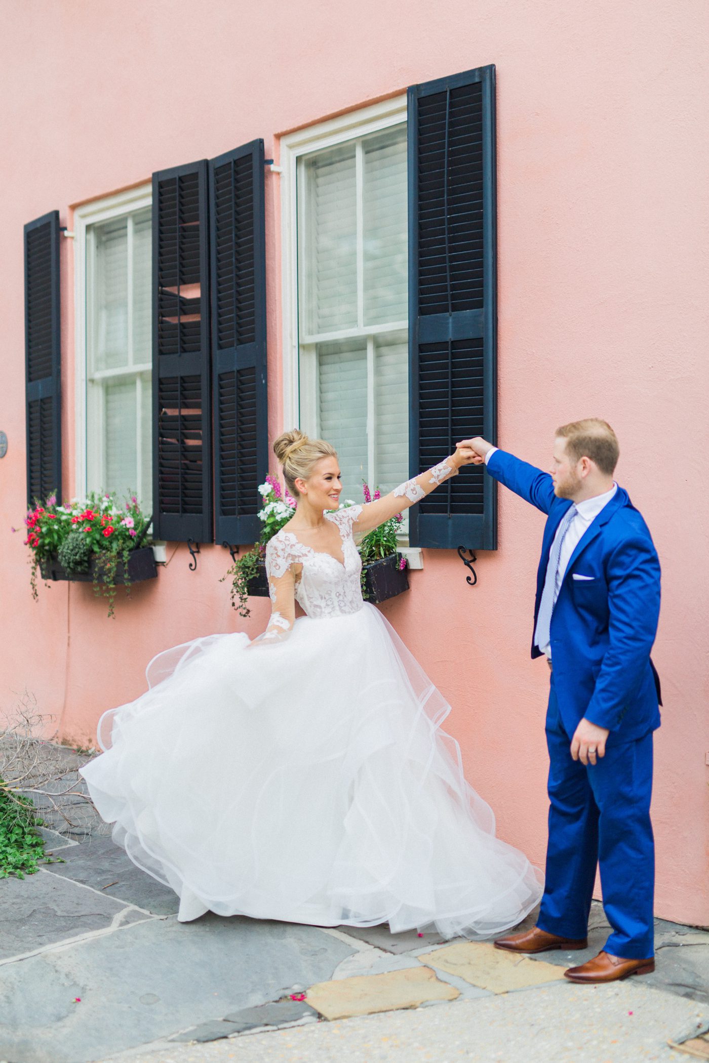 Charleston bride twirling in Hayley Paige gown against a historic pink house 