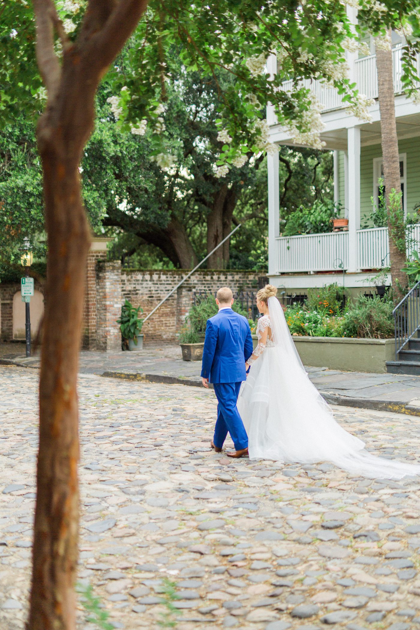 Bride and groom walking together down a cobblestone road in Charleston 