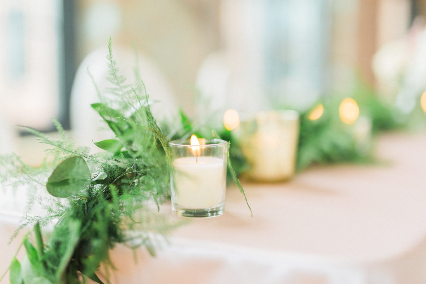 Candle lit reception with greenery table runner