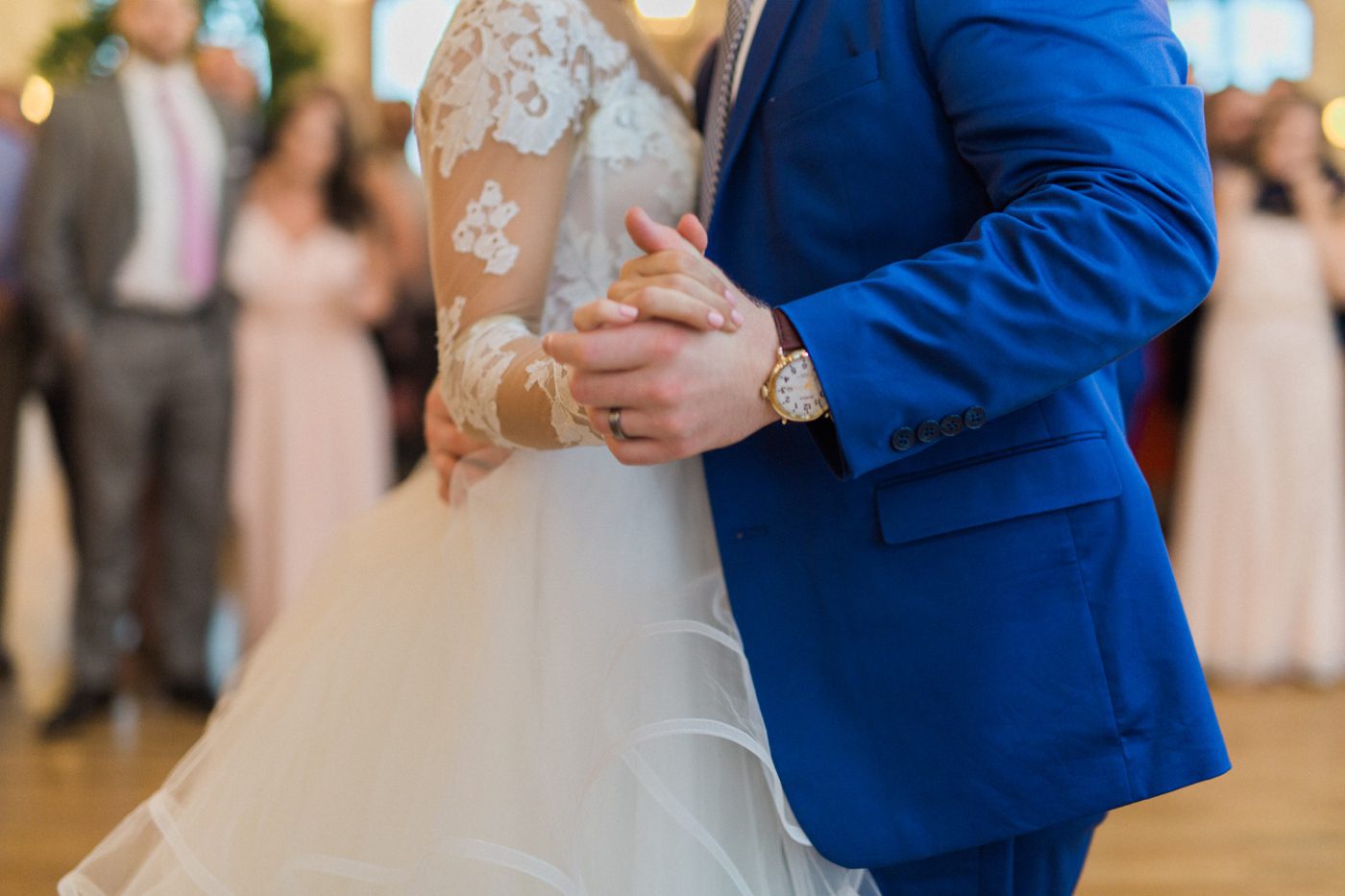 Close up photo of bride and groom holding hands while dancing