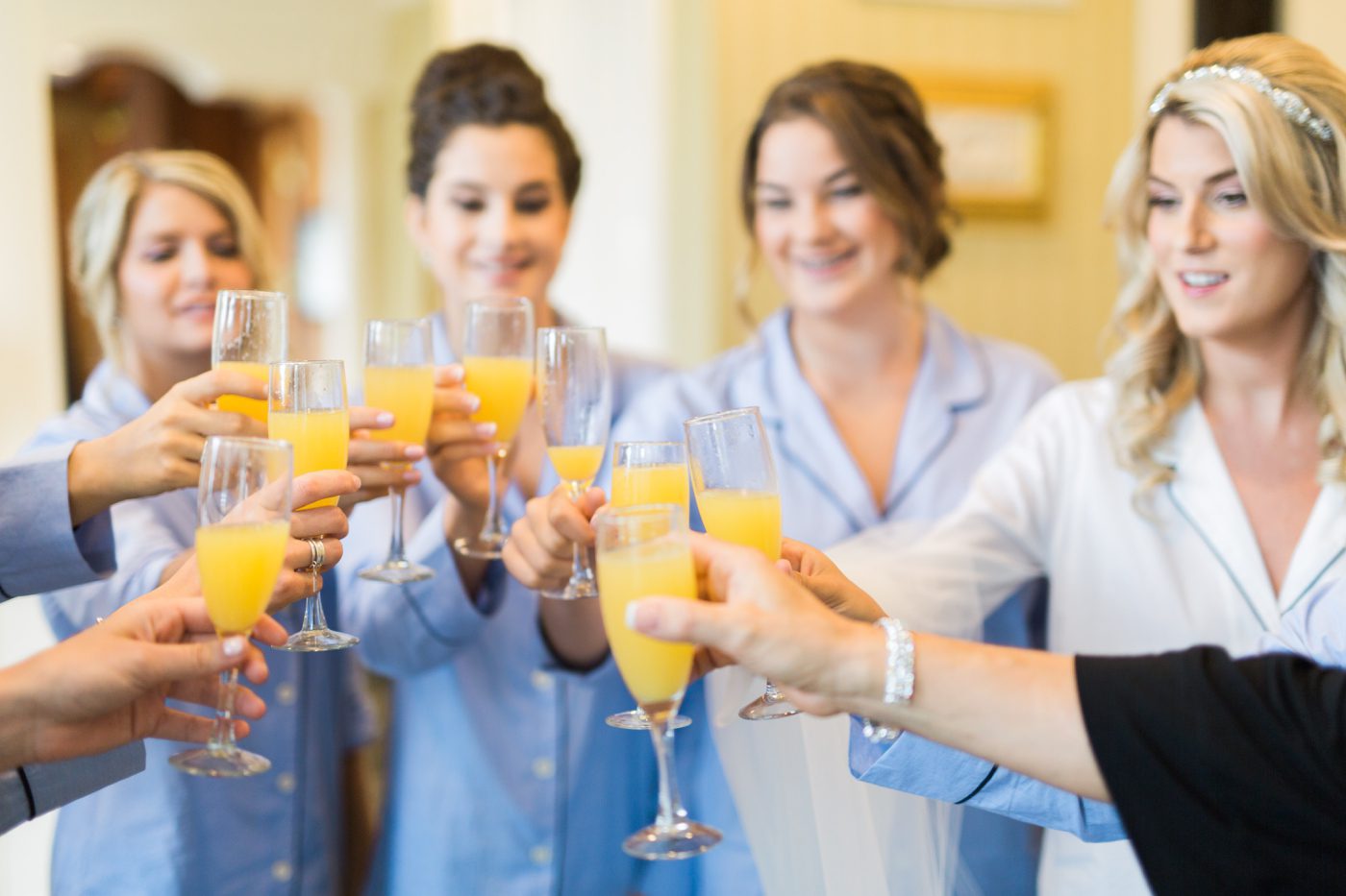 bride and bridesmaids cheersing with mimosas