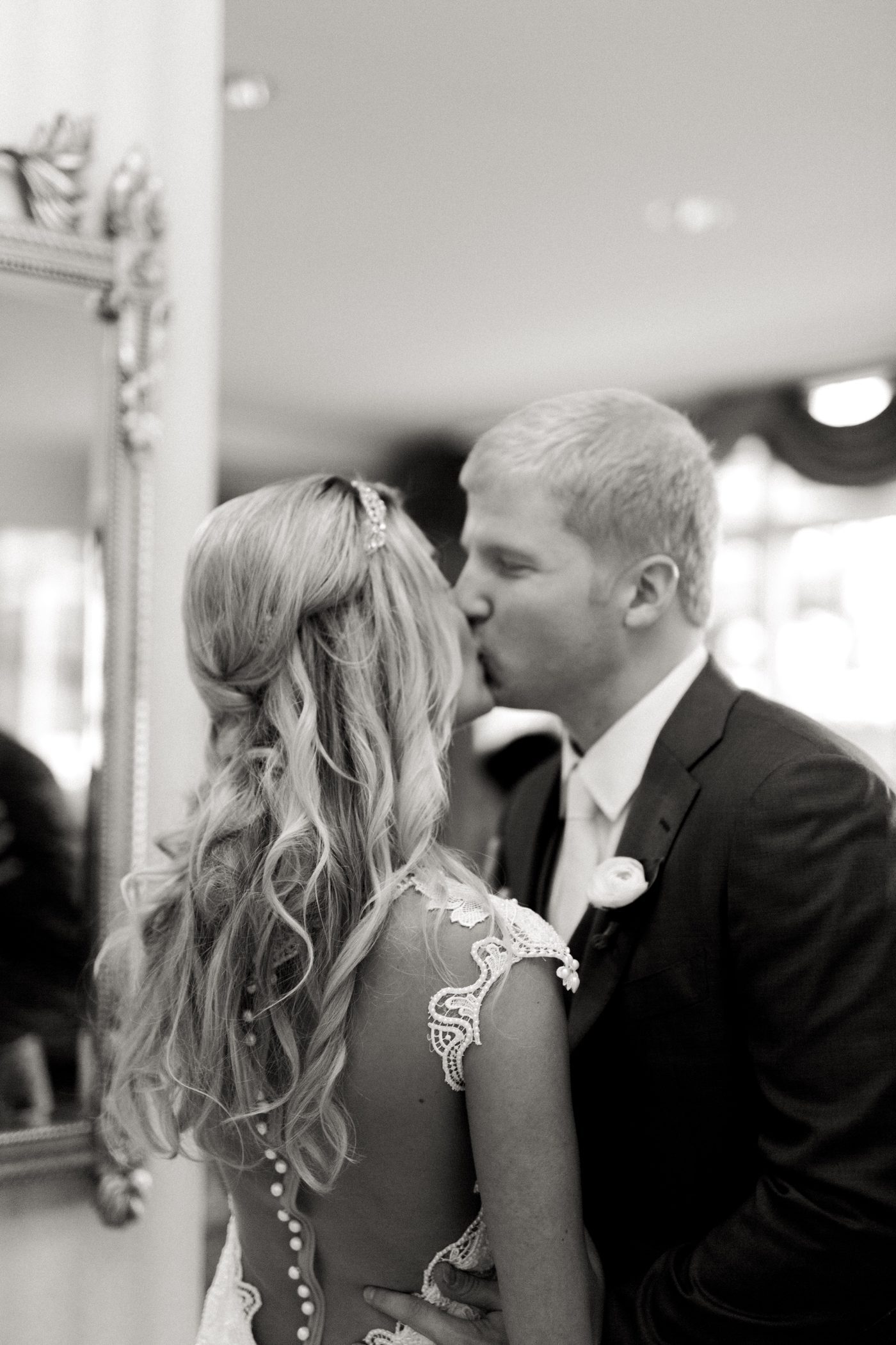 Black and white candid portrait of bride and groom kissing 