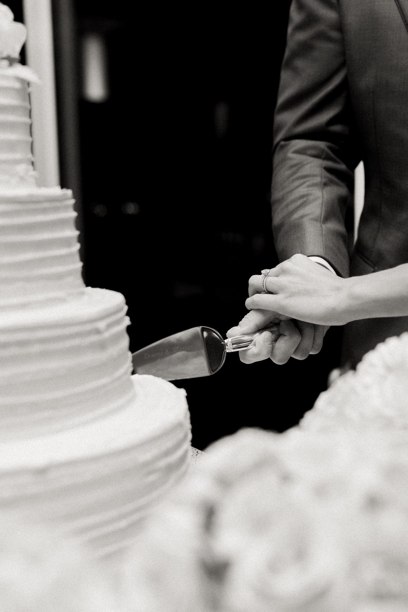 Couple cutting wedding cake with customized cake cutter 