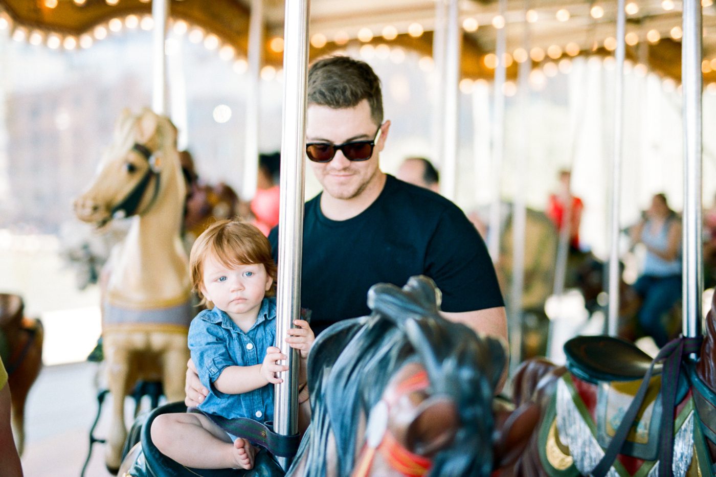 Red headed baby riding an antique carousel in NY