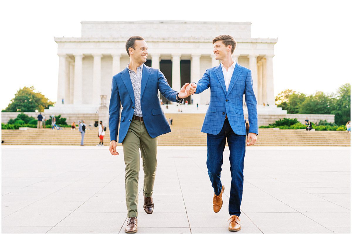 LGBTQ Washington DC engagement photo of two men holding hands and walking in front of the Lincoln Memorial