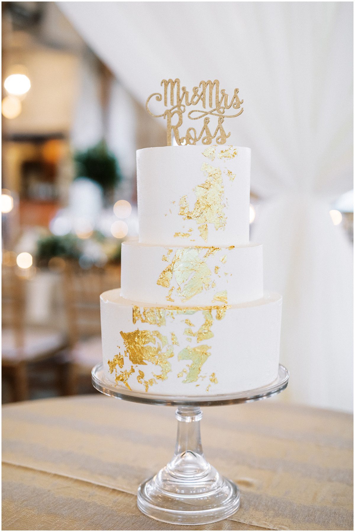 three tiered white wedding cake with gold foil detail