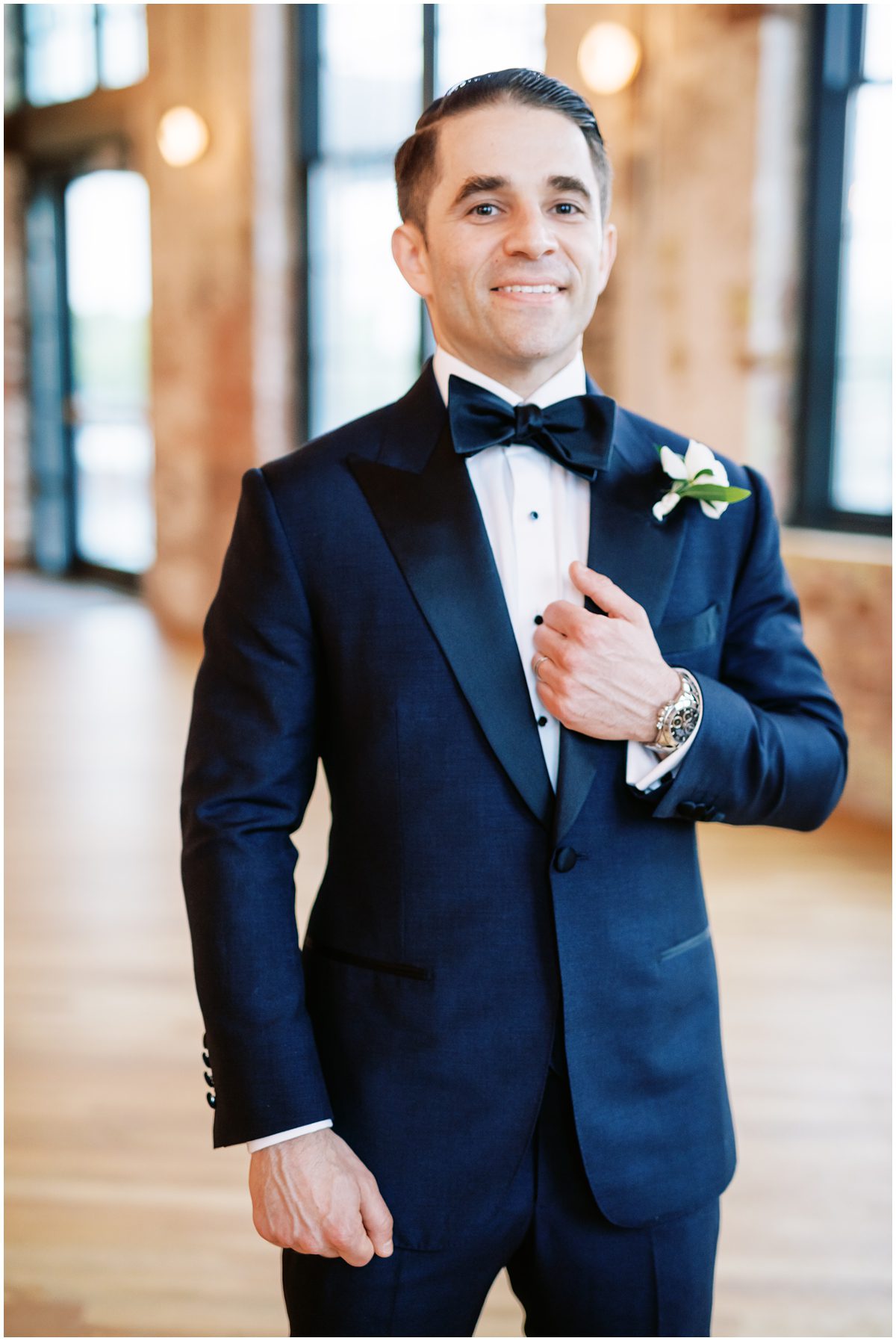Modern groom wearing a custom navy blue suit and bowtie with a Rolex watch