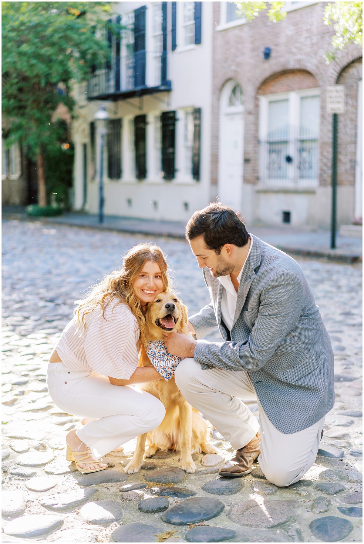 Engaged couple petting their dog on a cobblestone street in Charleston SC