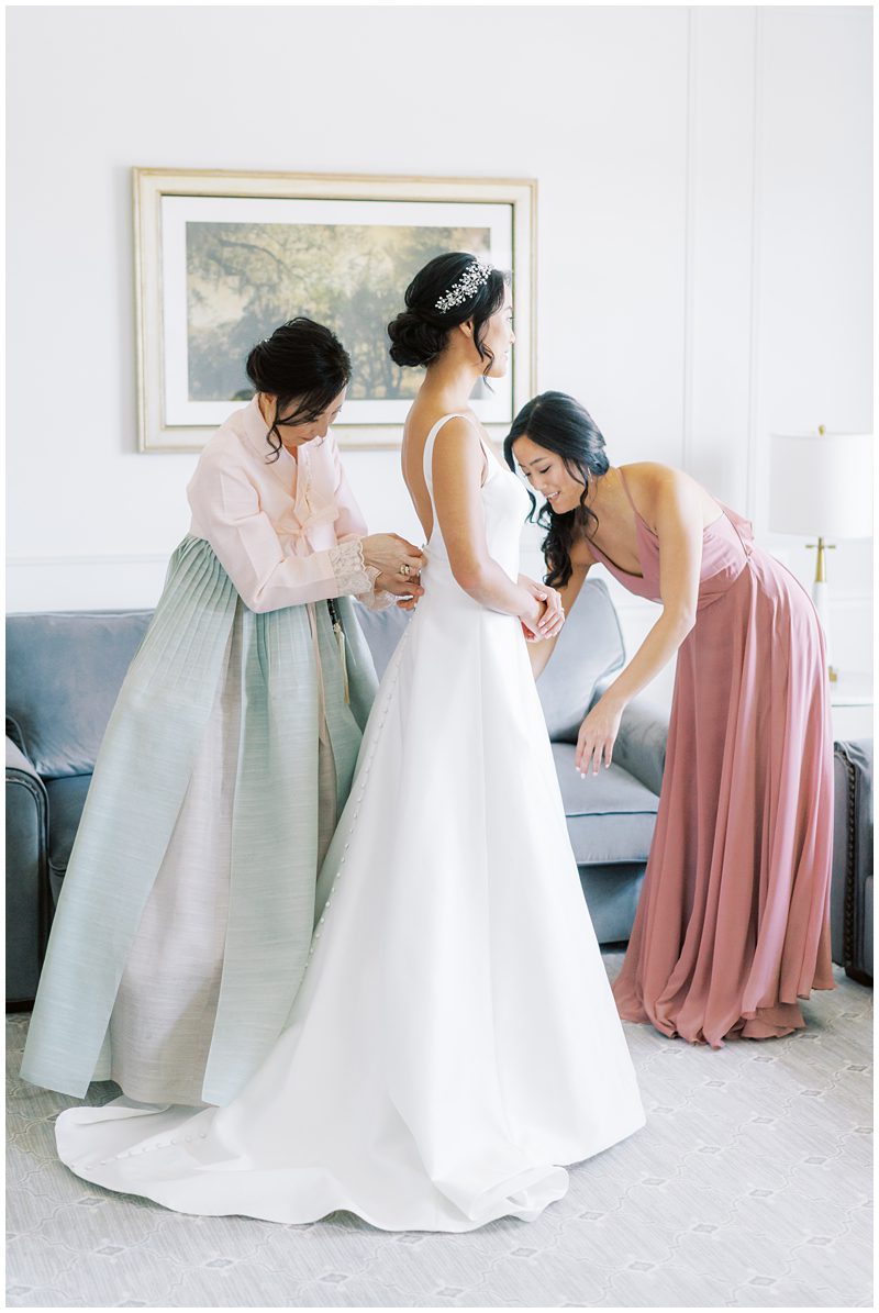 bride getting in her wedding dress with her mom wearing a blue and pink hanbok 