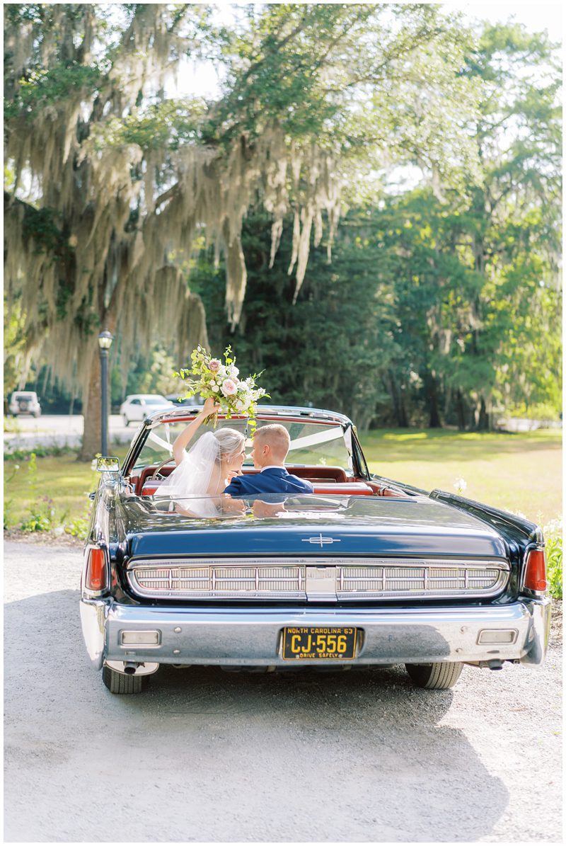 Bride and groom sitting in a vintage convertible at Magnolia Gardens in Charleston