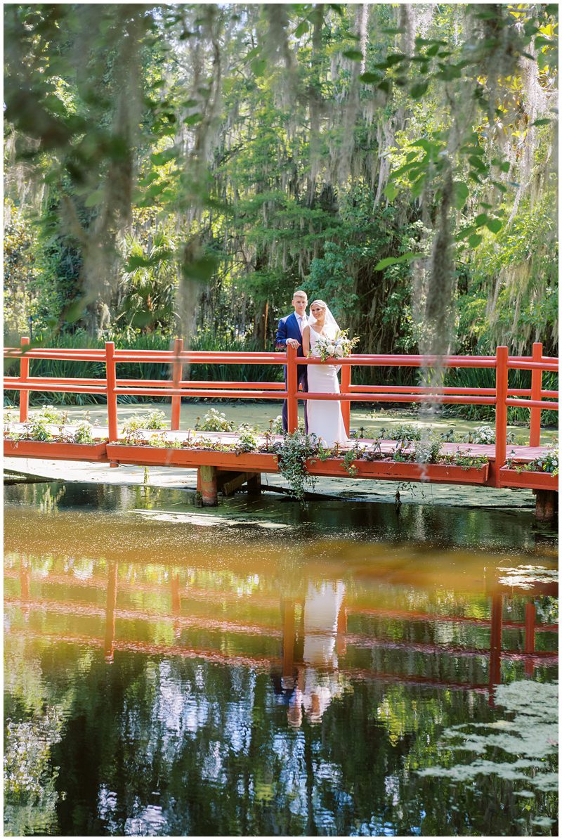 wedding photo of the couple standing on the red bridge at Magnolia in Charleston