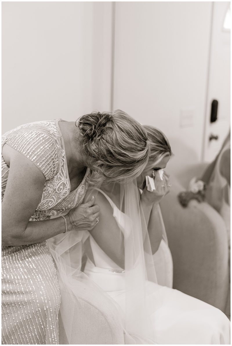 emotional black and white photo of the bride crying and her mom hugging her