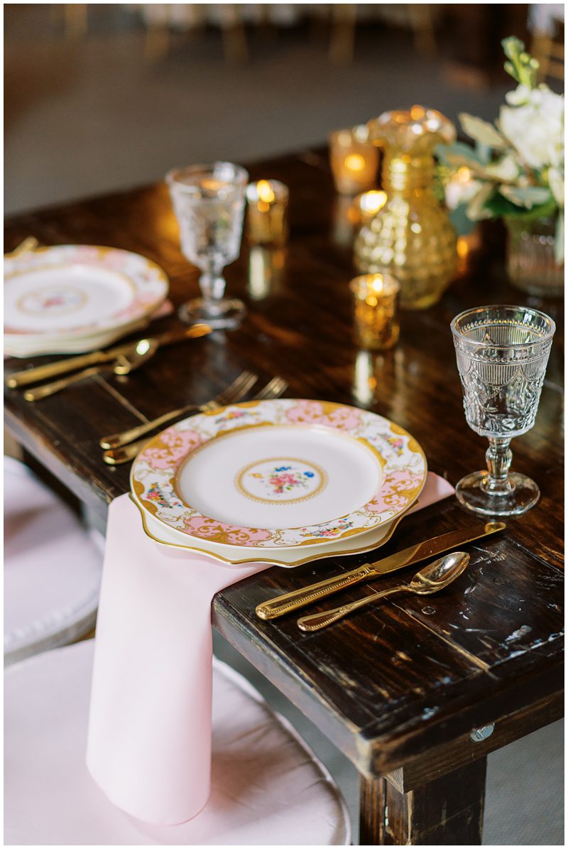 pink and gold wedding reception decor with vintage plates and clear goblets