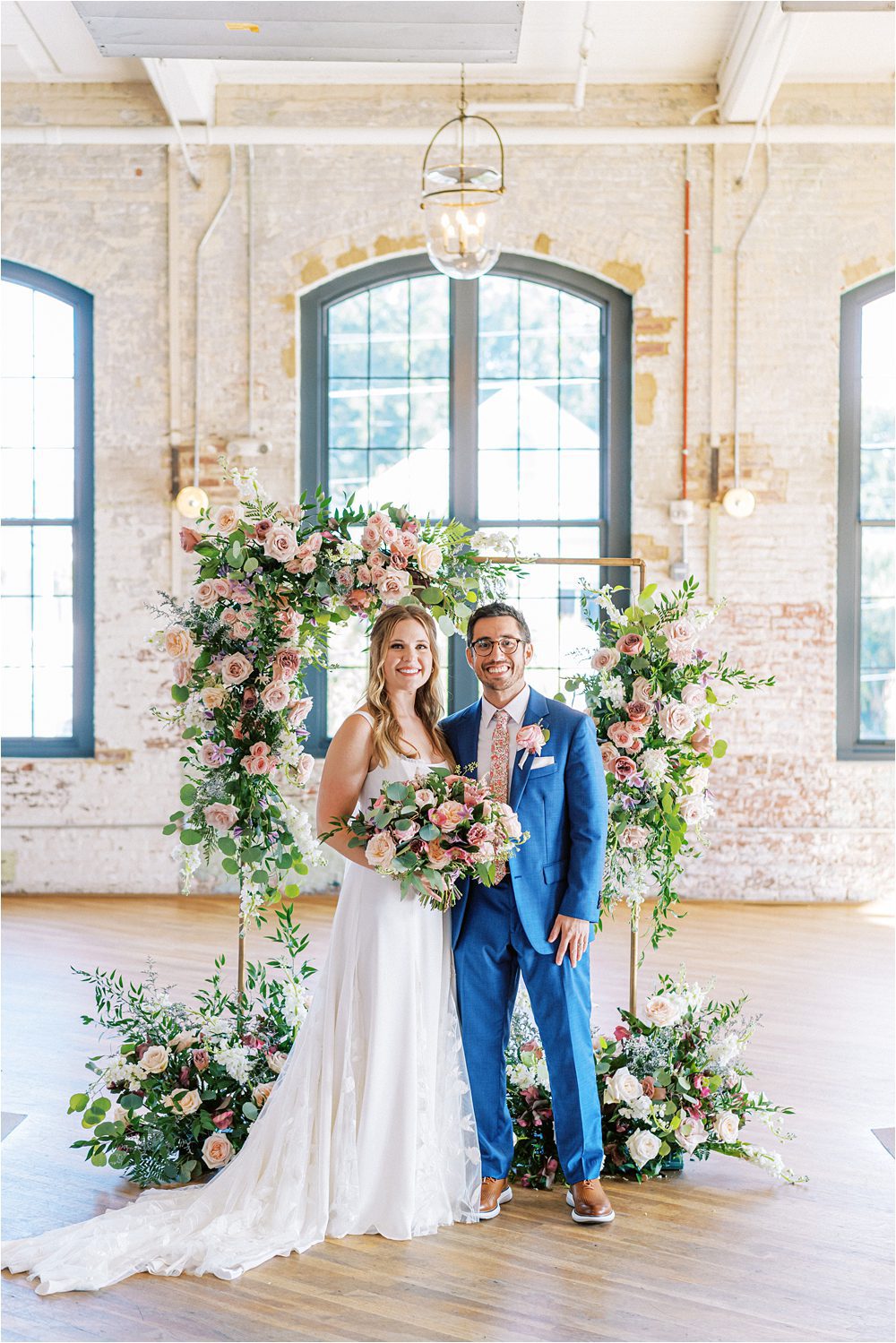 wedding photo of the bride and groom in front of a floral arch