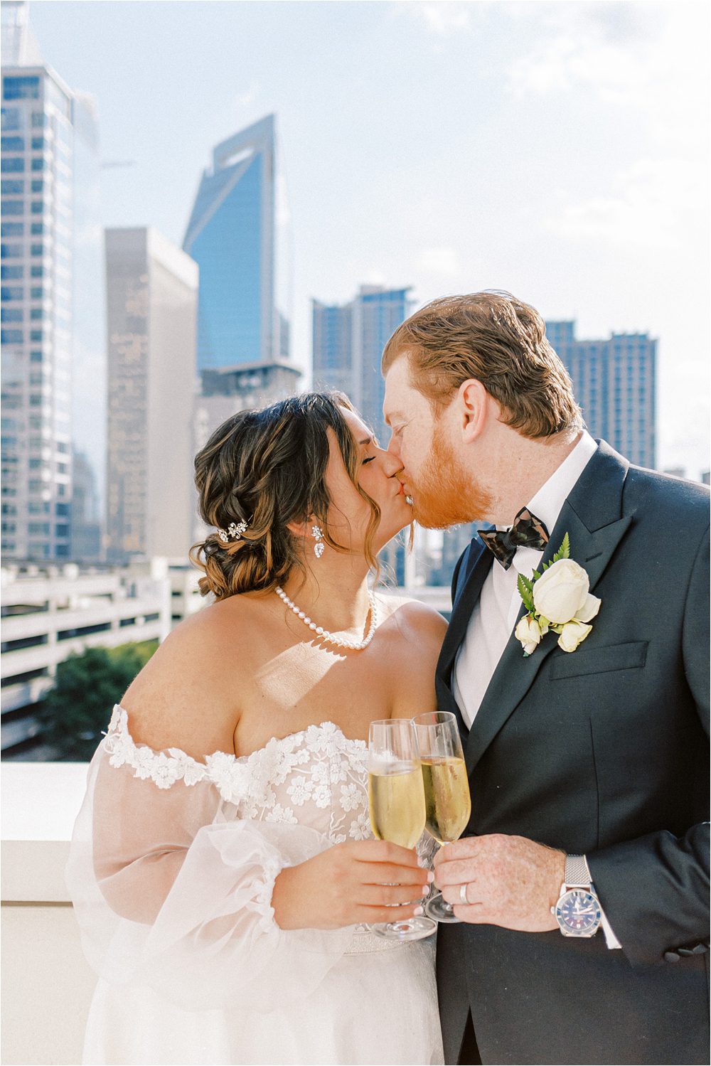 bride and groom toasting with champagne after their ceremony with downtown Charlotte NC in the background
