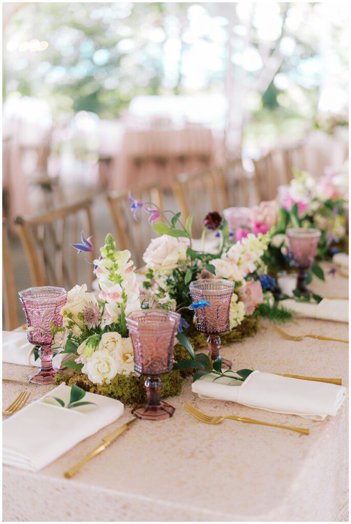 romantic garden inspired wedding reception decor with lots of flowers and purple goblets