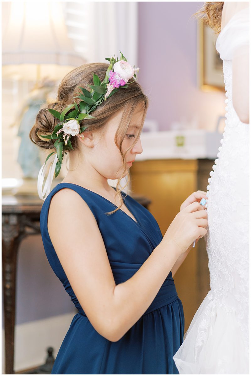 daughter of the bride buttoning her wedding dress