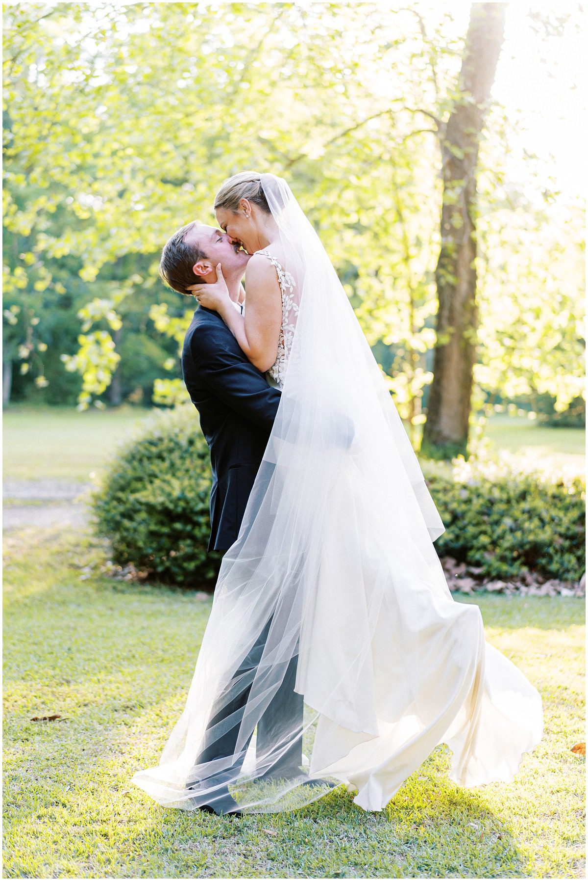 romantic wedding portrait of the groom picking up the bride and kissing her