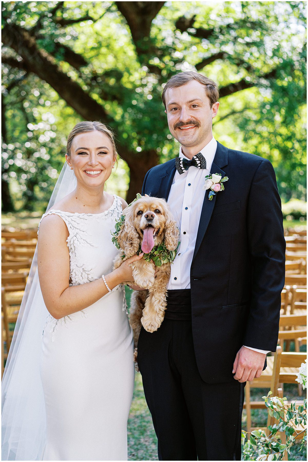 bride and groom holding their cocker spaniel wearing a flower crown