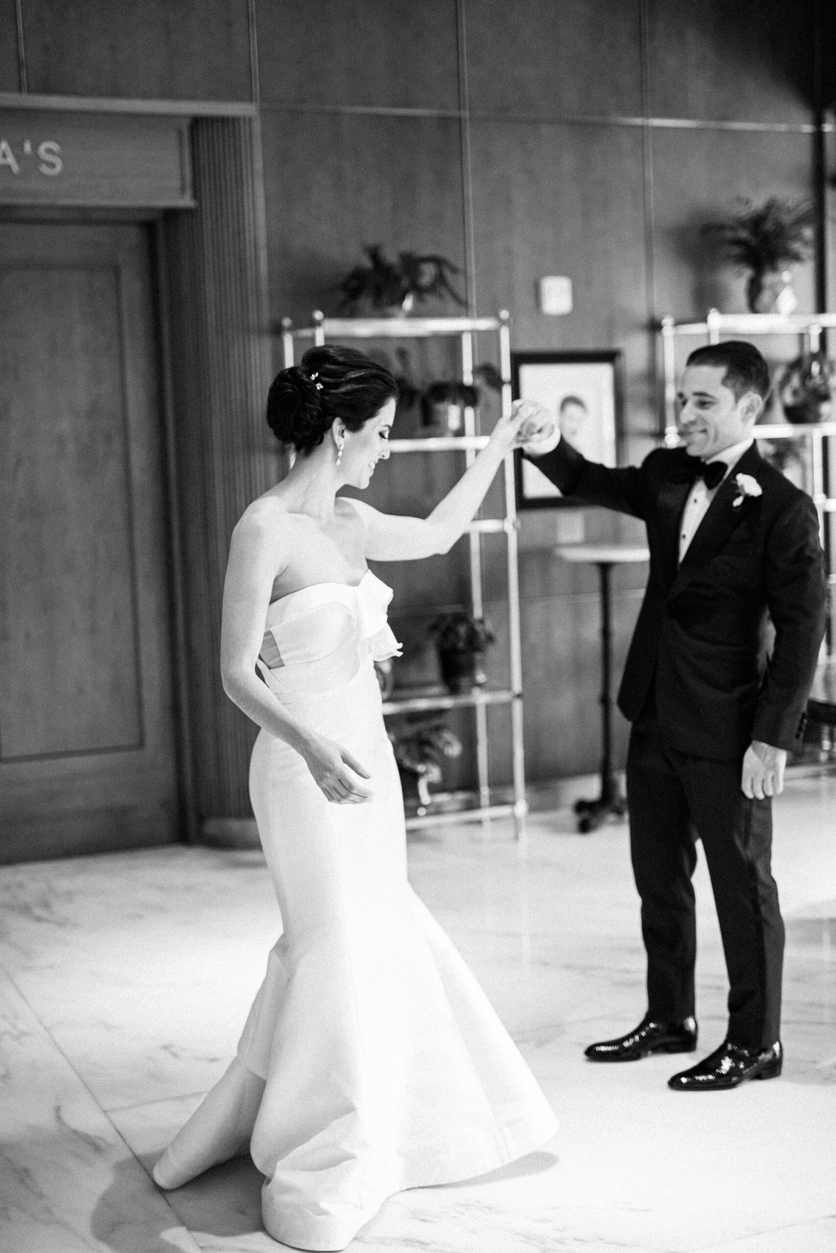 Candid moment of a well dressed groom twirling his fashionable bride in the lobby of the Dewberry Hotel in Charleston