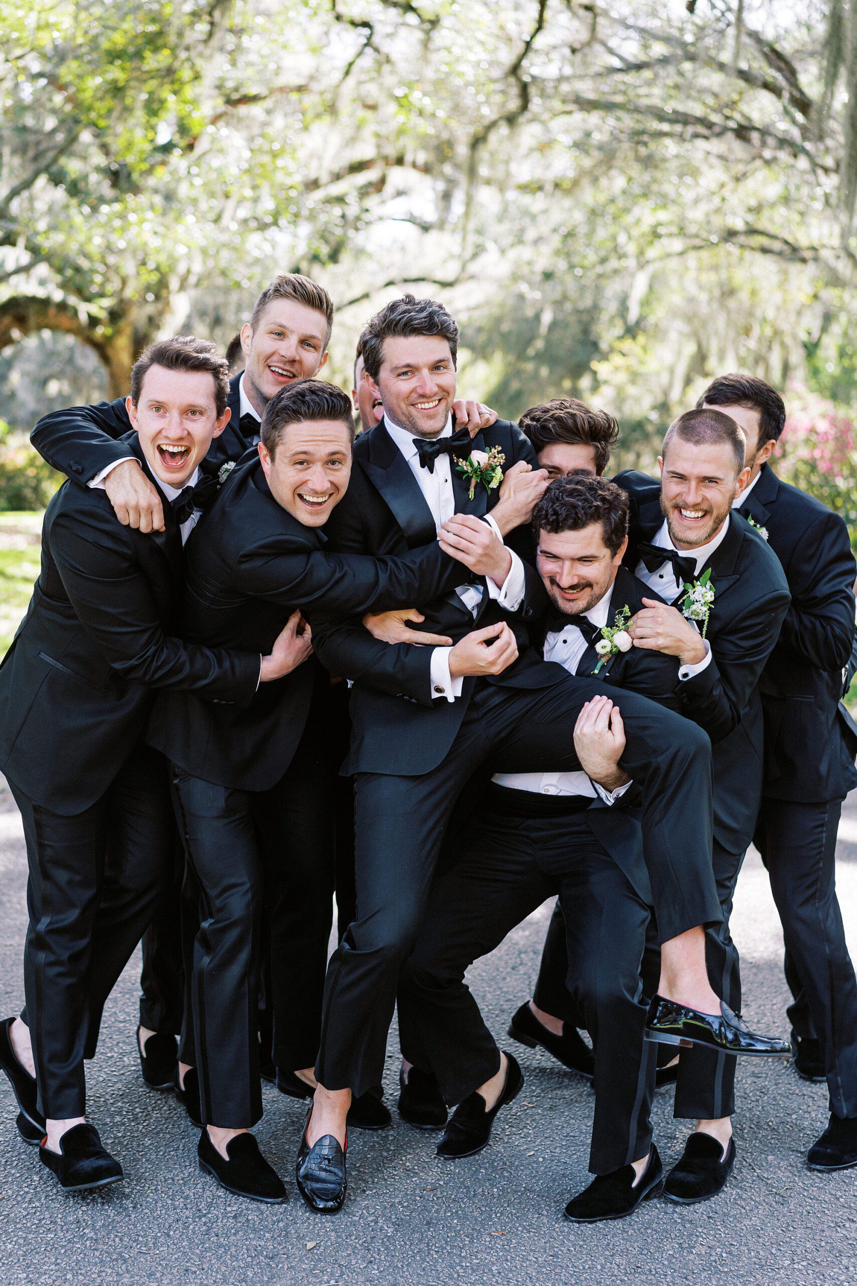 A stylish groom sharing a fun moment with his groomsmen at Magnolia Plantation and Gardens