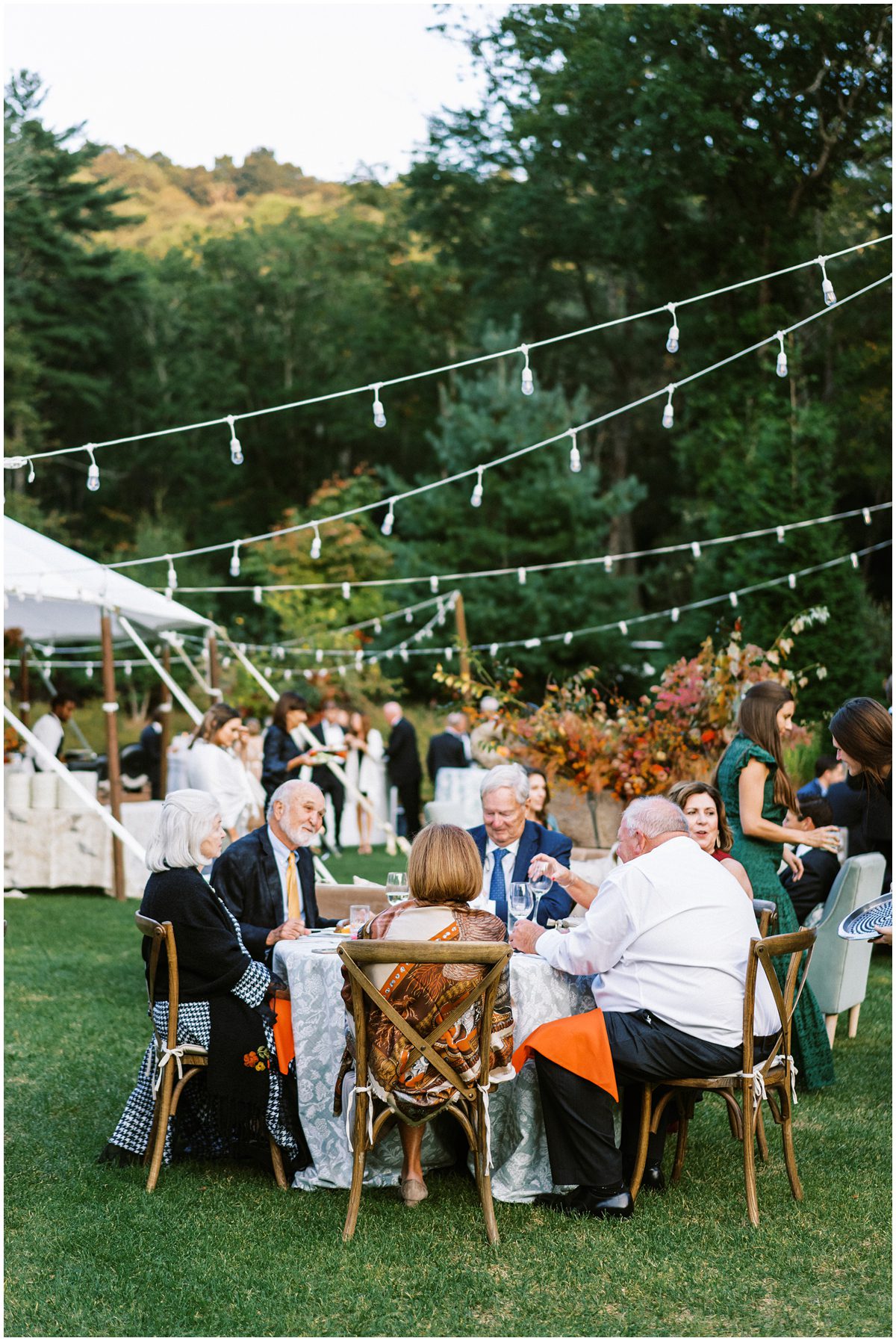 Guests sitting around a table during the cocktail hour at a luxury fall wedding in Highlands NC