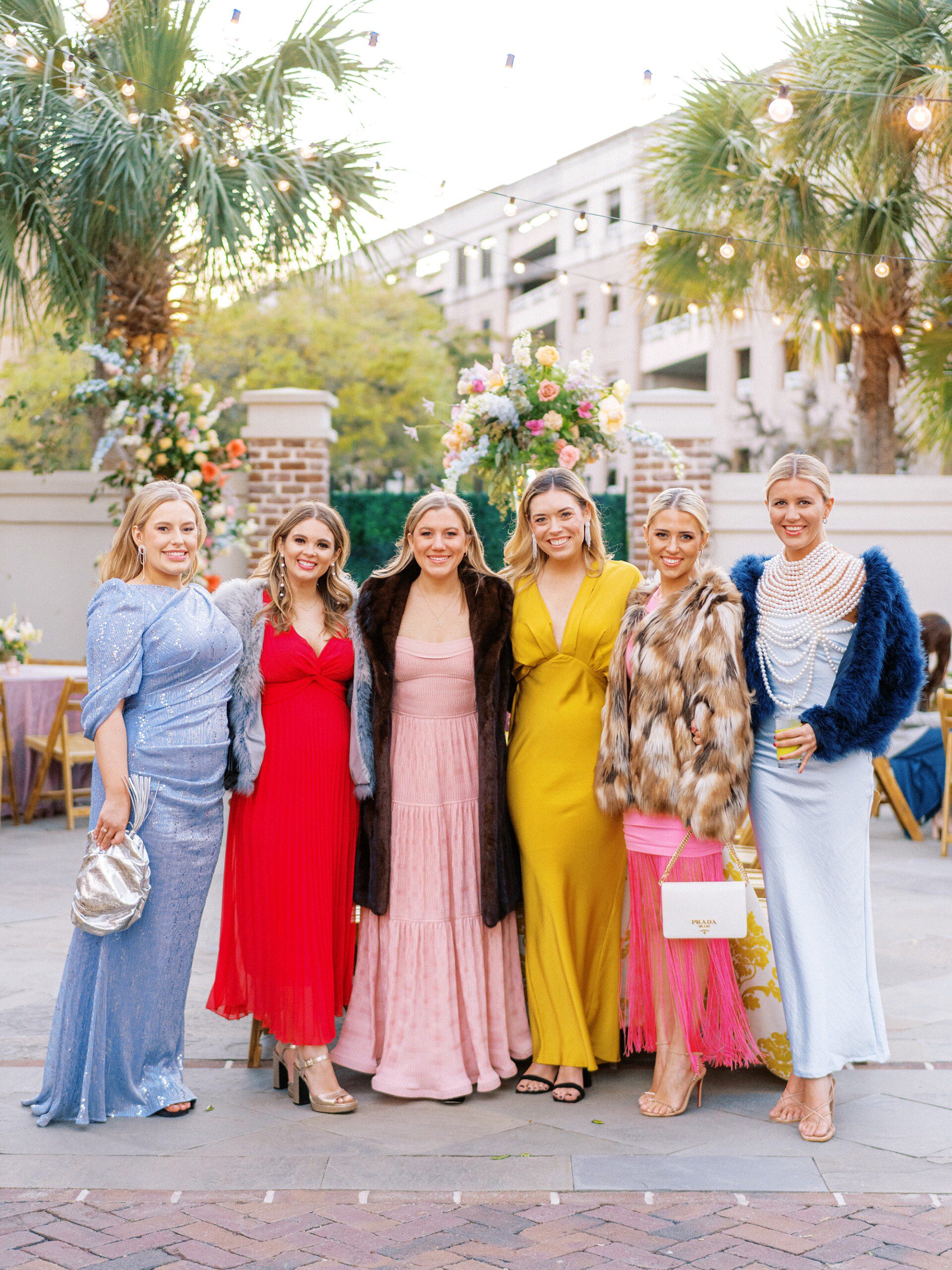 Fashionable wedding guests at cocktail hour at the Gadsden House wearing pink and yellow dresses and a Prada bag