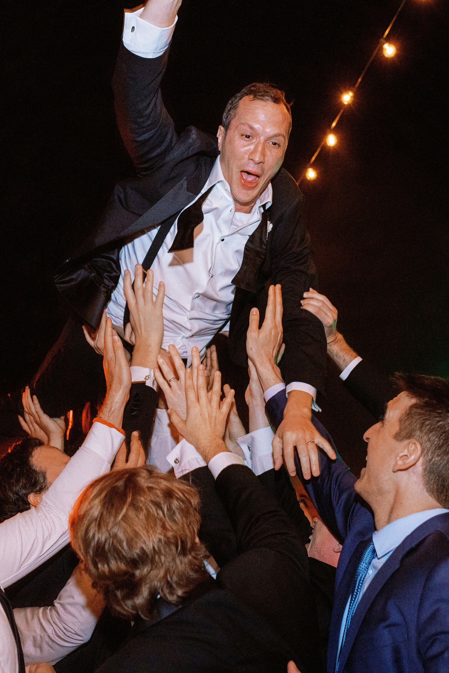 a groom crowd surfing at his wedding reception at Middleton Place