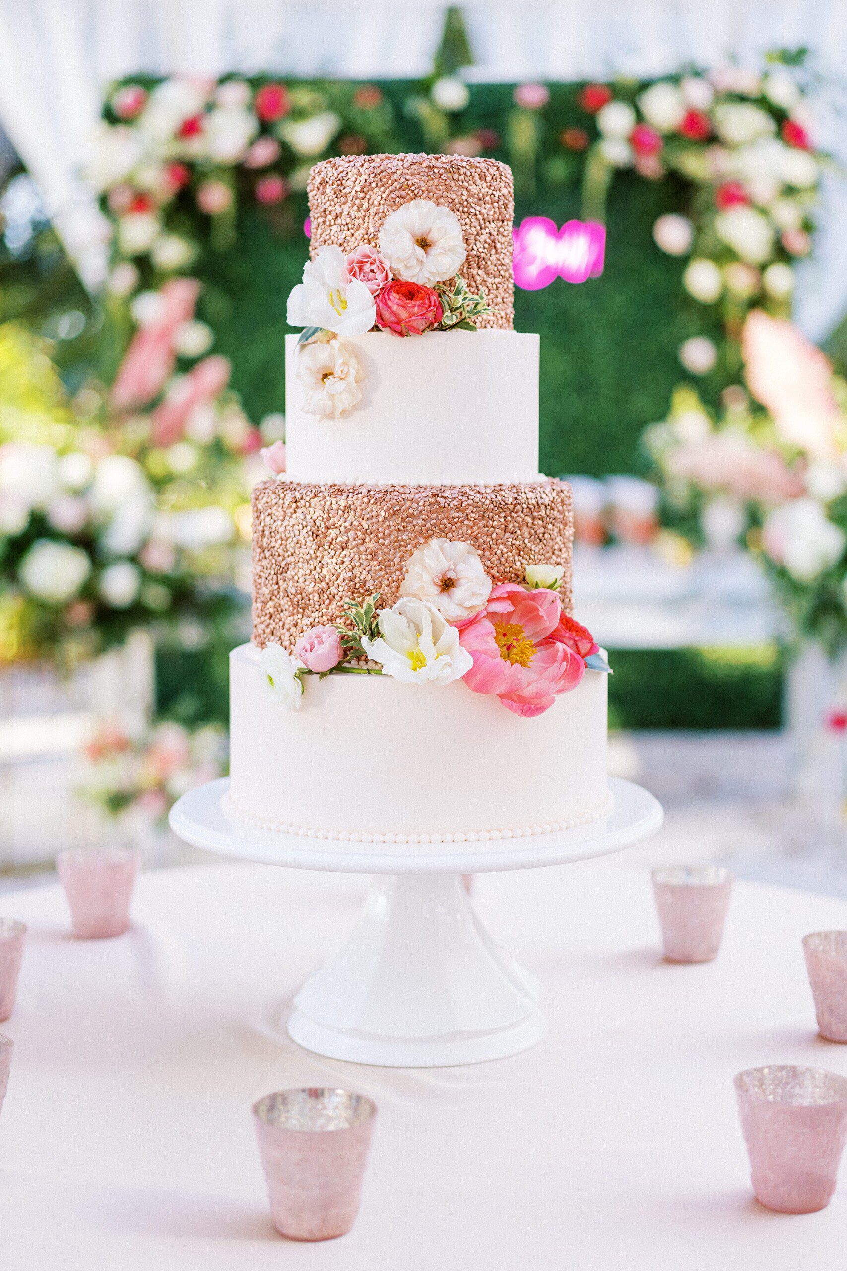 A gorgeous four tiered wedding cake with rose gold pebbling and pink flowers at a Lowndes Grove wedding reception