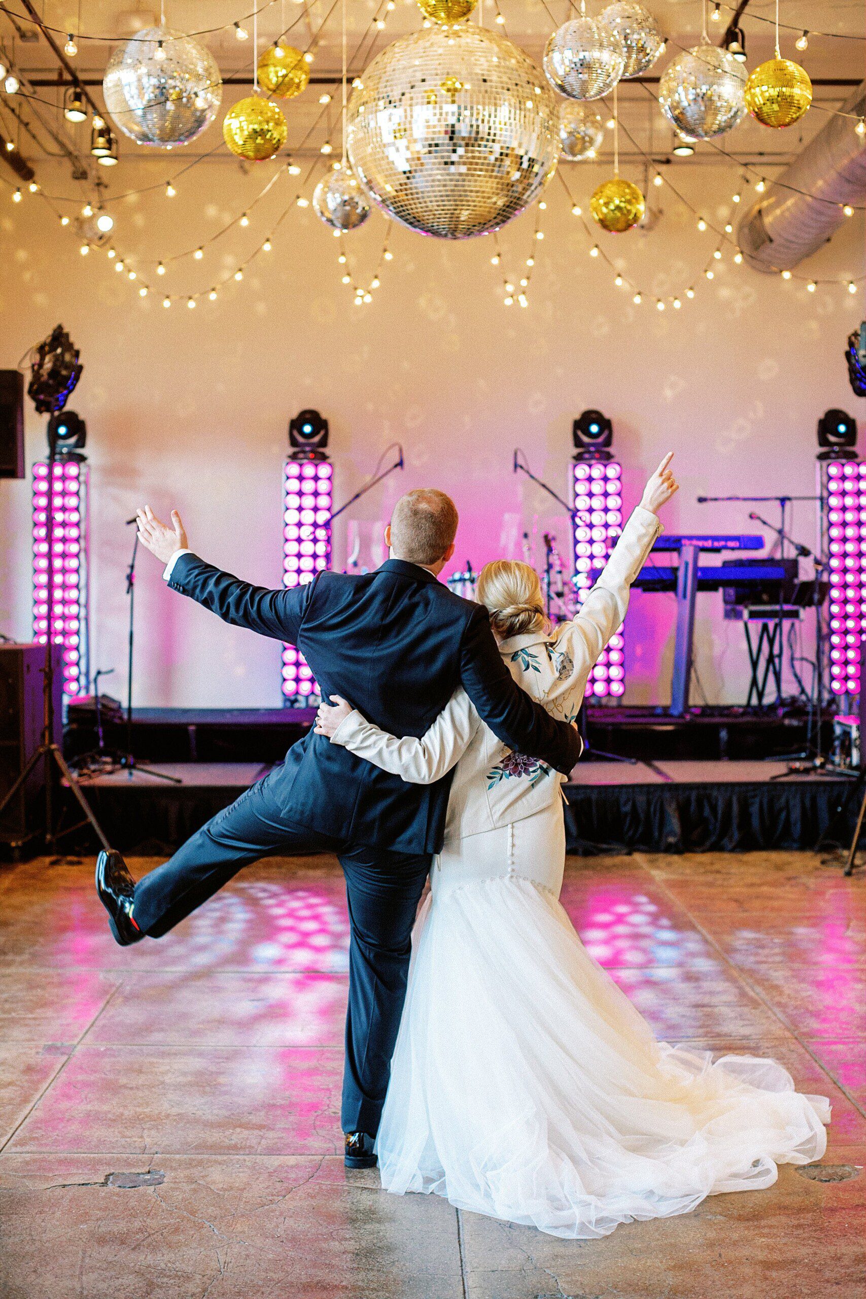Bride wearing a painted leather jacket and a groom under disco balls at their wedding reception
