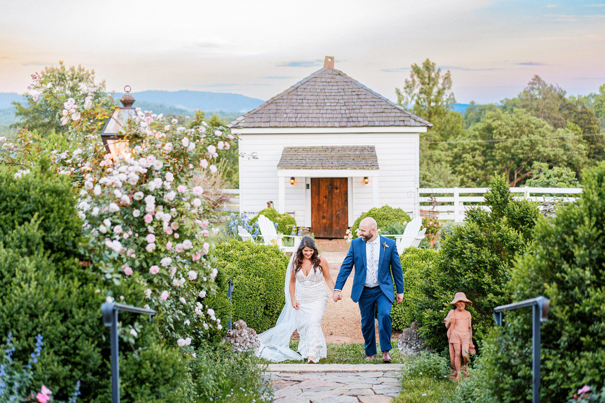 bride and groom walking through a garden with the blue ridge mountains in the back at their luxury destination wedding in Virginia