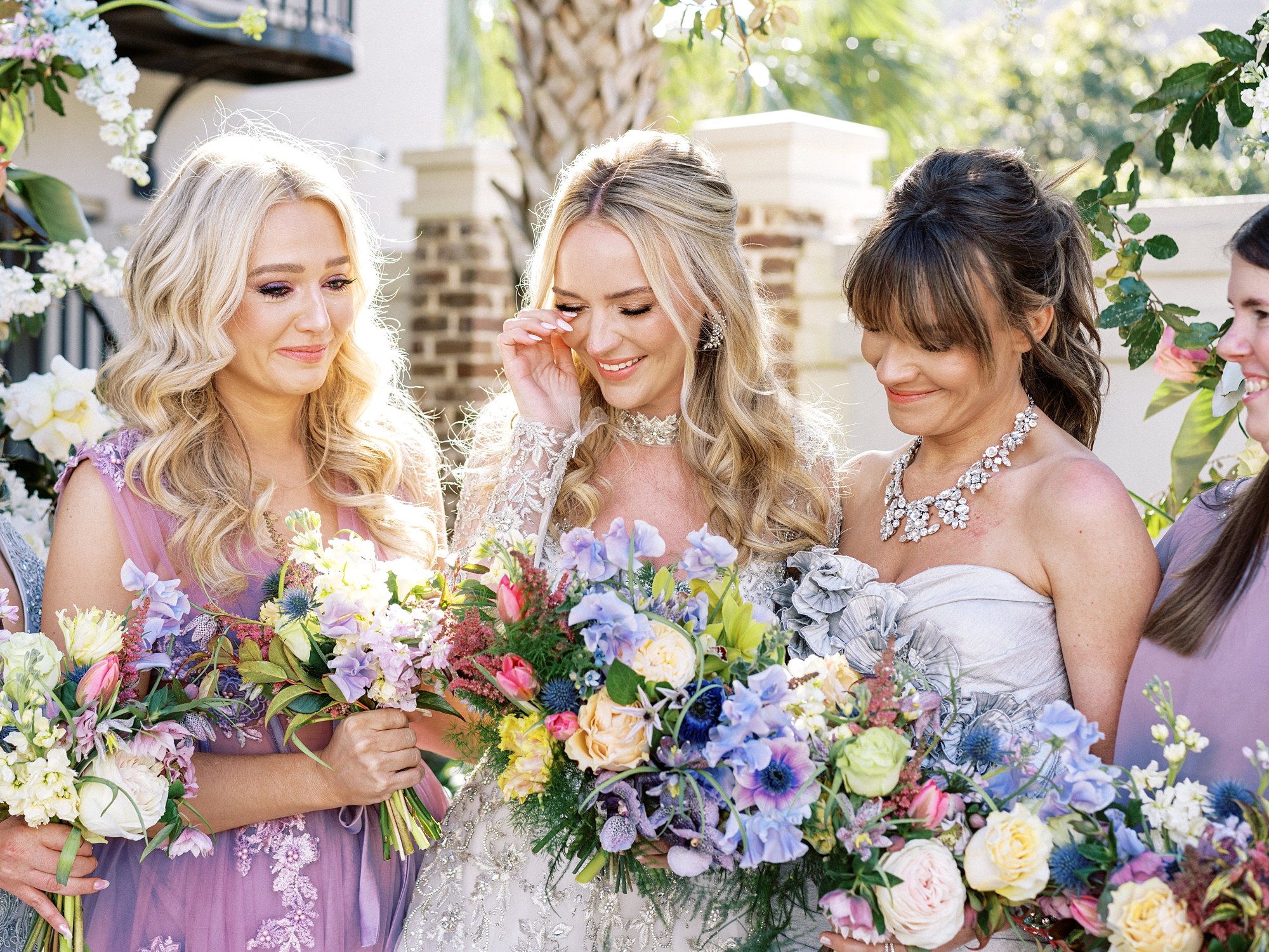 A very fashionable bride wiping a tear away with her bridesmaids crying too at her Charleston wedding
