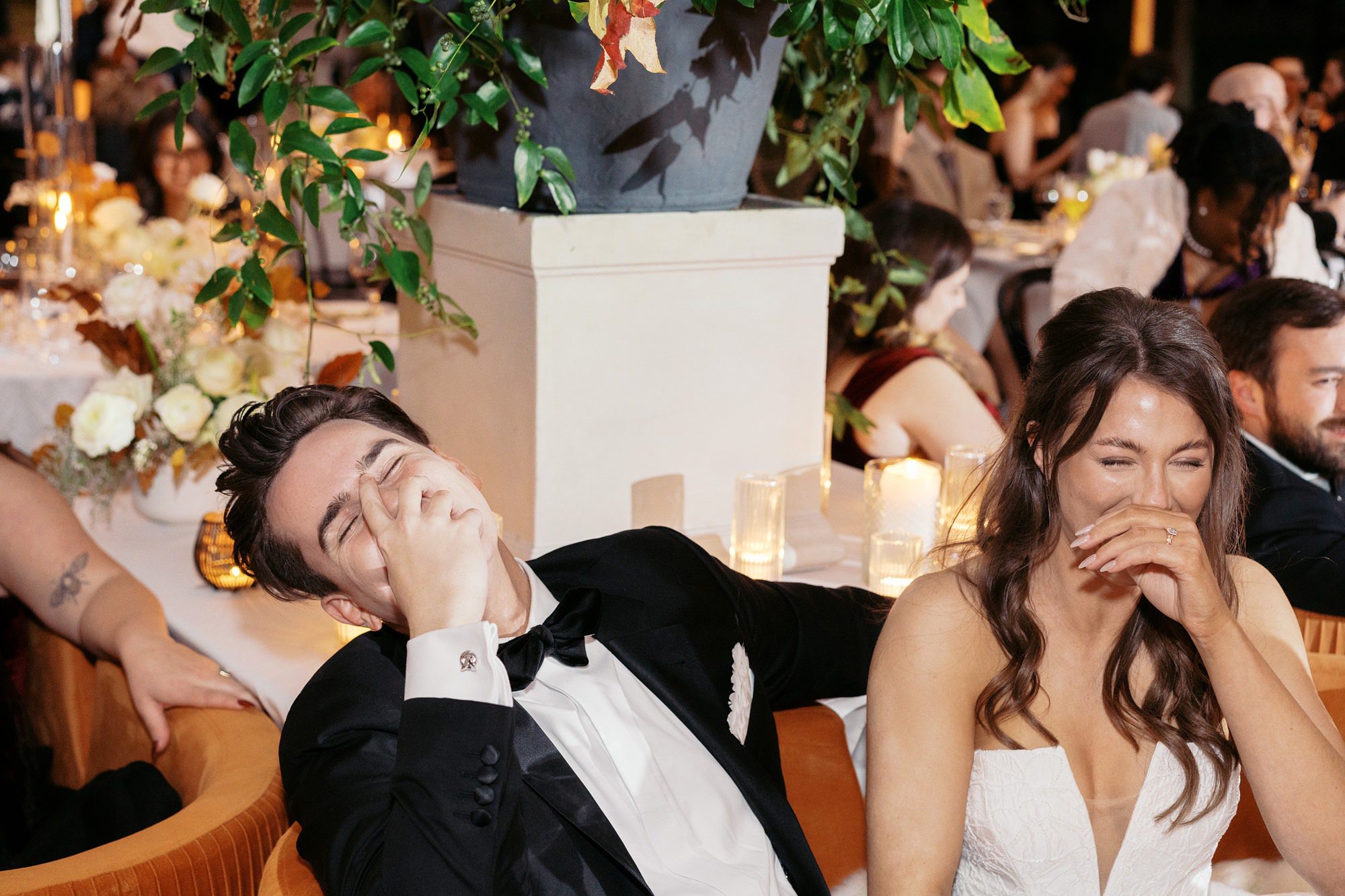 A candid photo of a bride and groom laughing together during an outdoor tented wedding reception a a Marie Selby Gardens wedding.