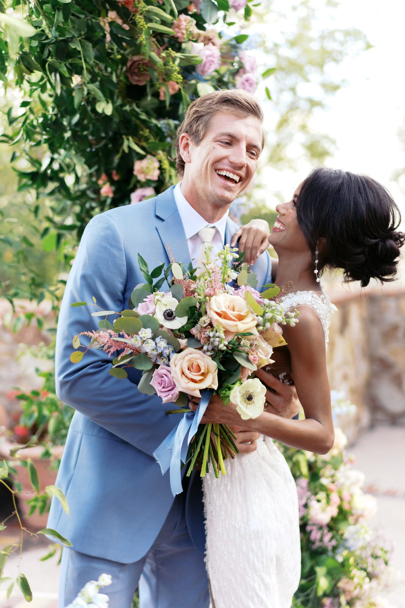 candid photo of the bride and groom laughing under their ceremony arch at Bella Collina
